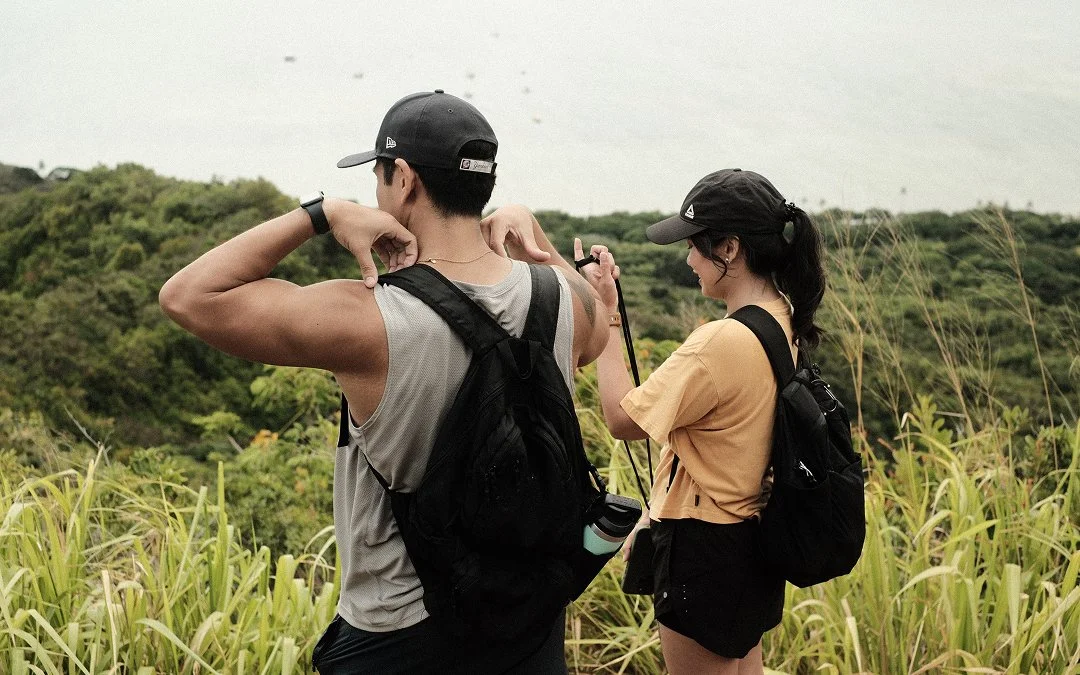 Two hikers adjusting backpacks above tall grass overlooking Kaneohe Bay, shot with the Yakisugi Green film recipe