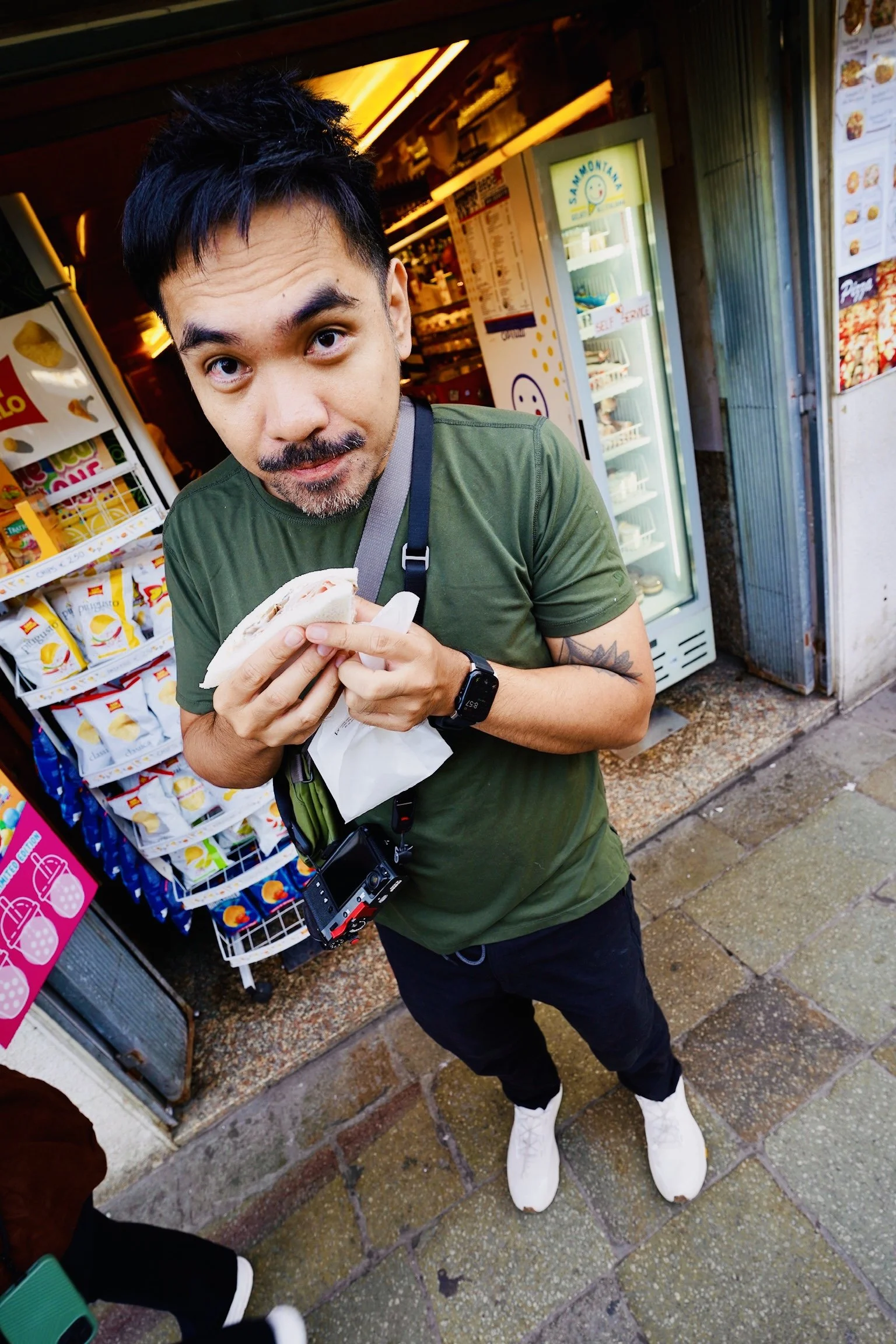 A man eating a tramezzino sandwich outside a Venice snack bar