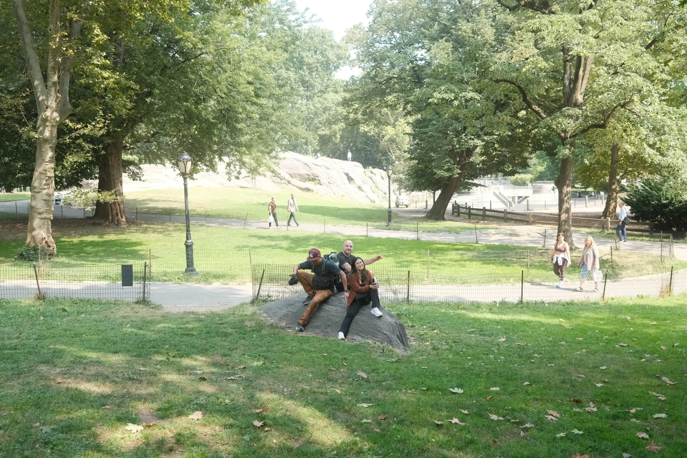 Three friends posing on a boulder in Central Park