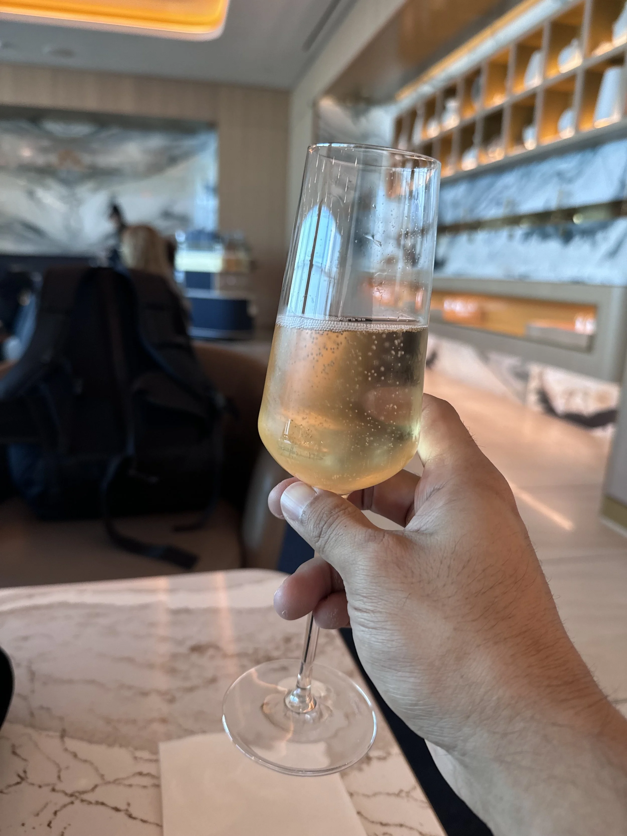 Raising a glass of sparkling wine in an airport lounge