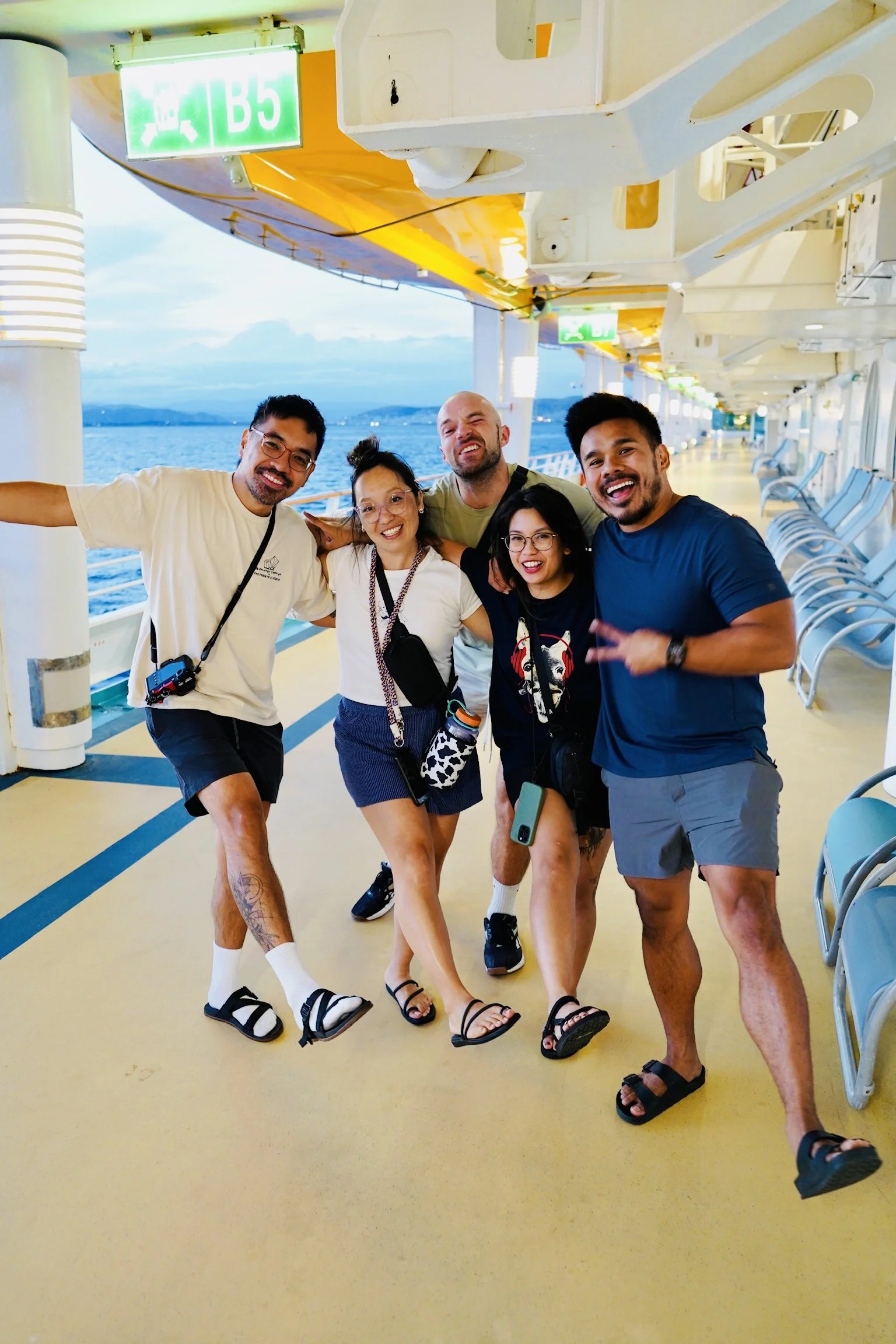 Five friends striking dance poses on the cruise ship deck at dusk