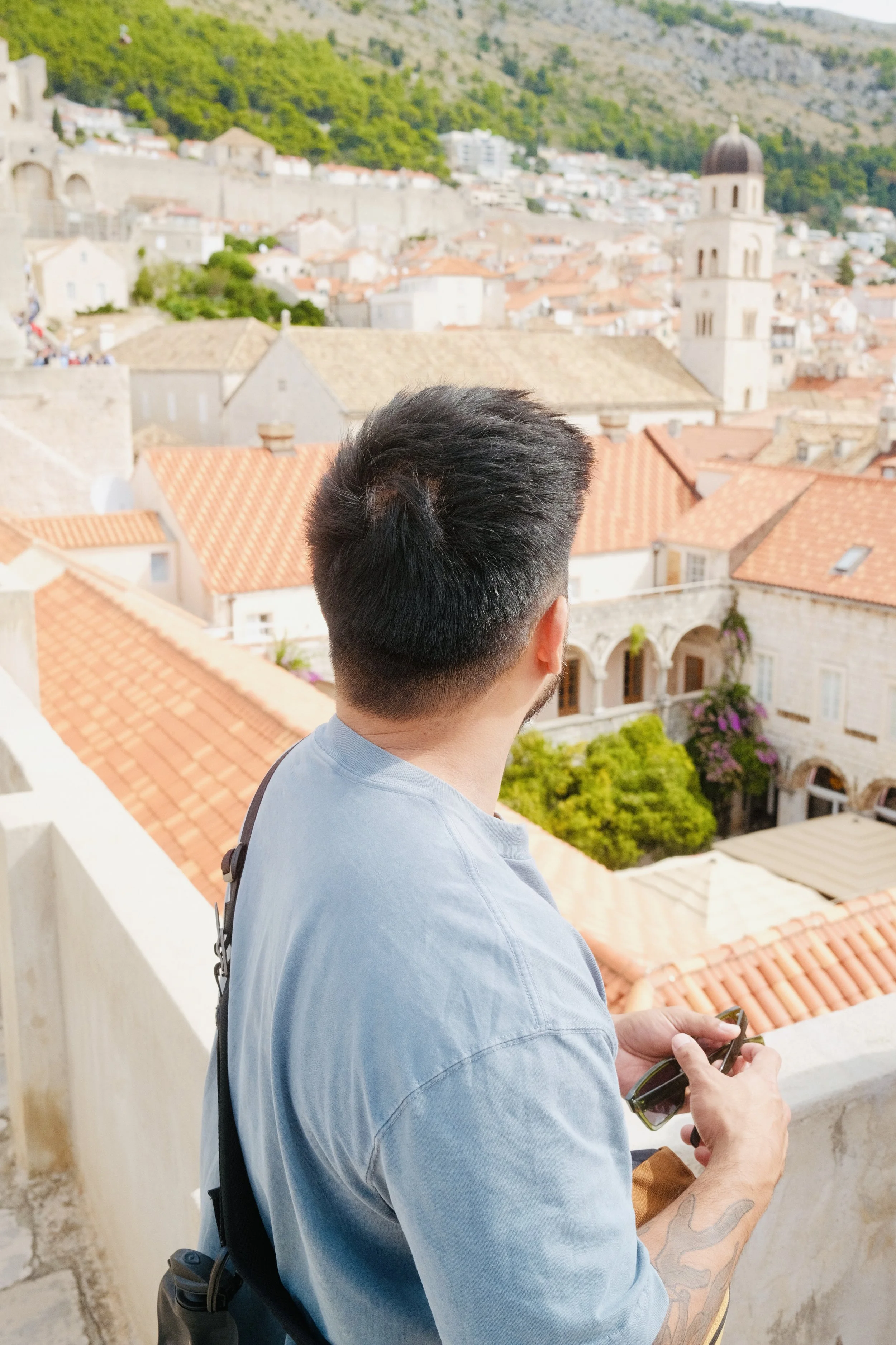 A man looking out over Dubrovnik's terracotta rooftops from the city walls