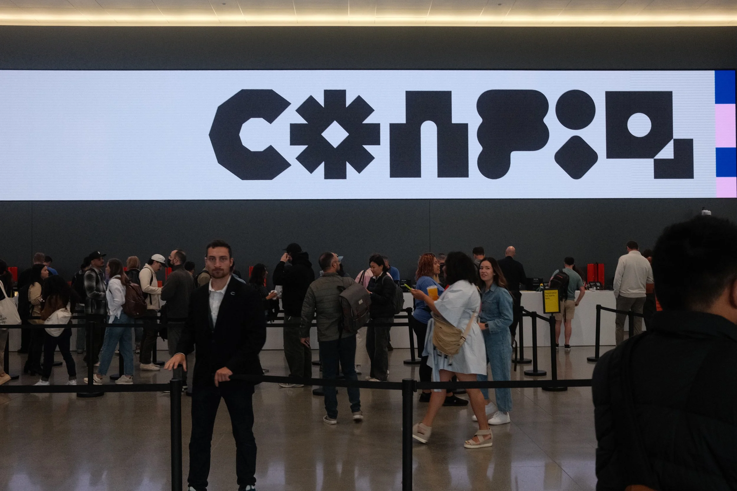 Attendees line up at Config conference registration beneath a giant Figma Config logo screen