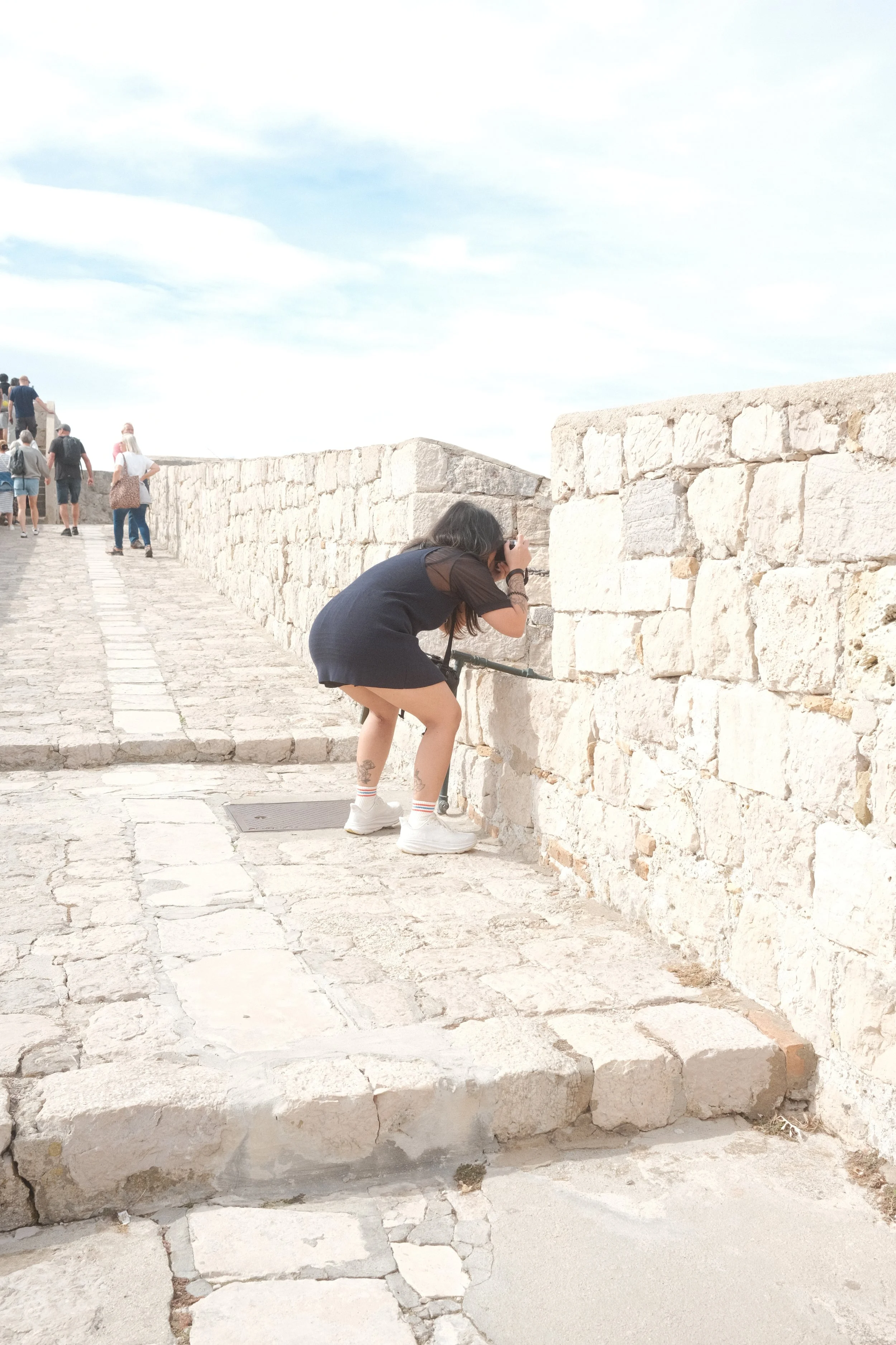 A woman taking photos over the parapet of Dubrovnik's city walls