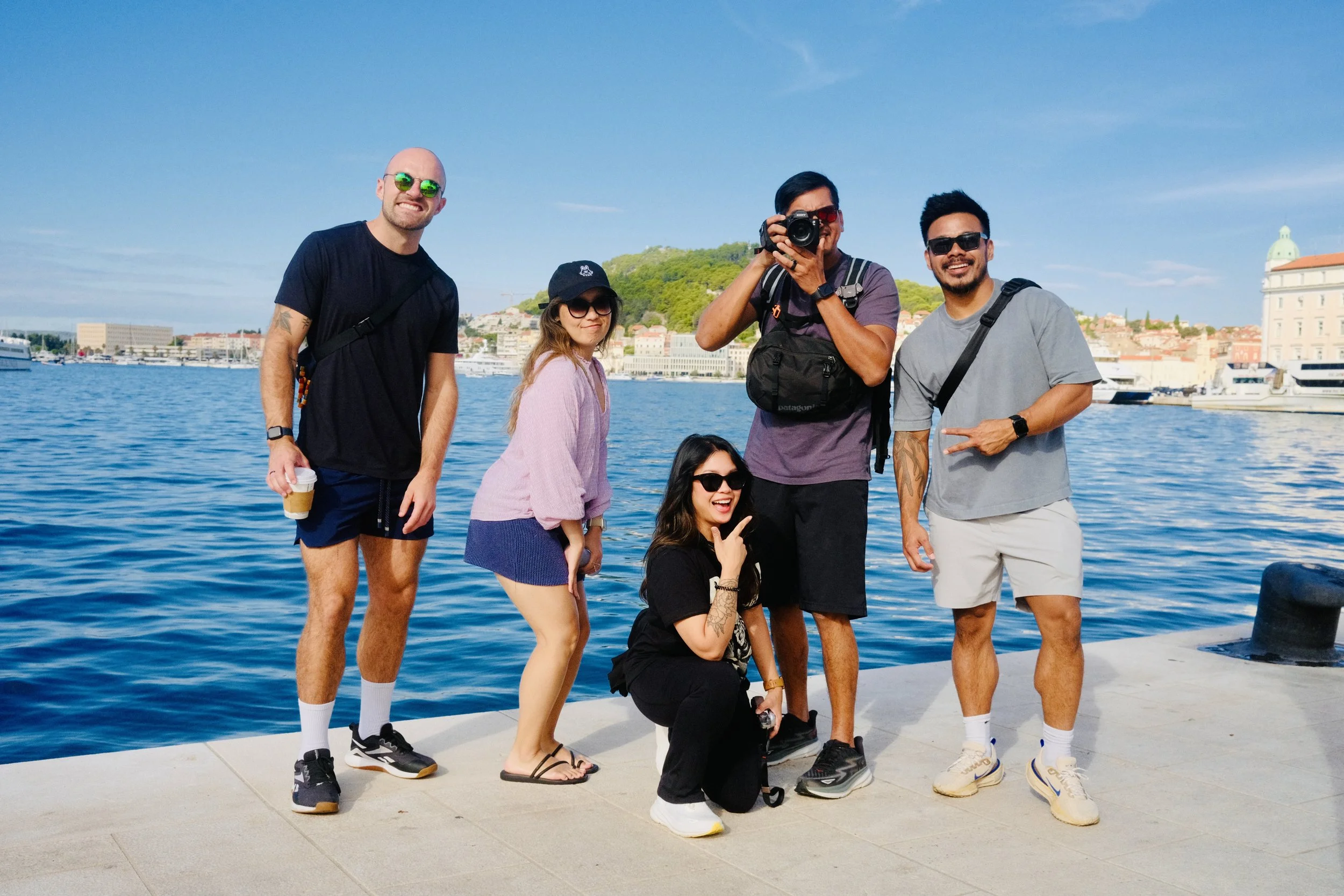 Five friends posing on Split's waterfront promenade with the harbor behind
