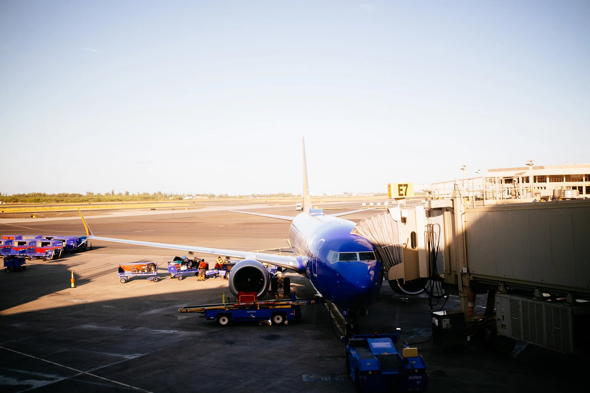 Southwest Airlines jet being loaded at gate E7 on a sunny airport tarmac