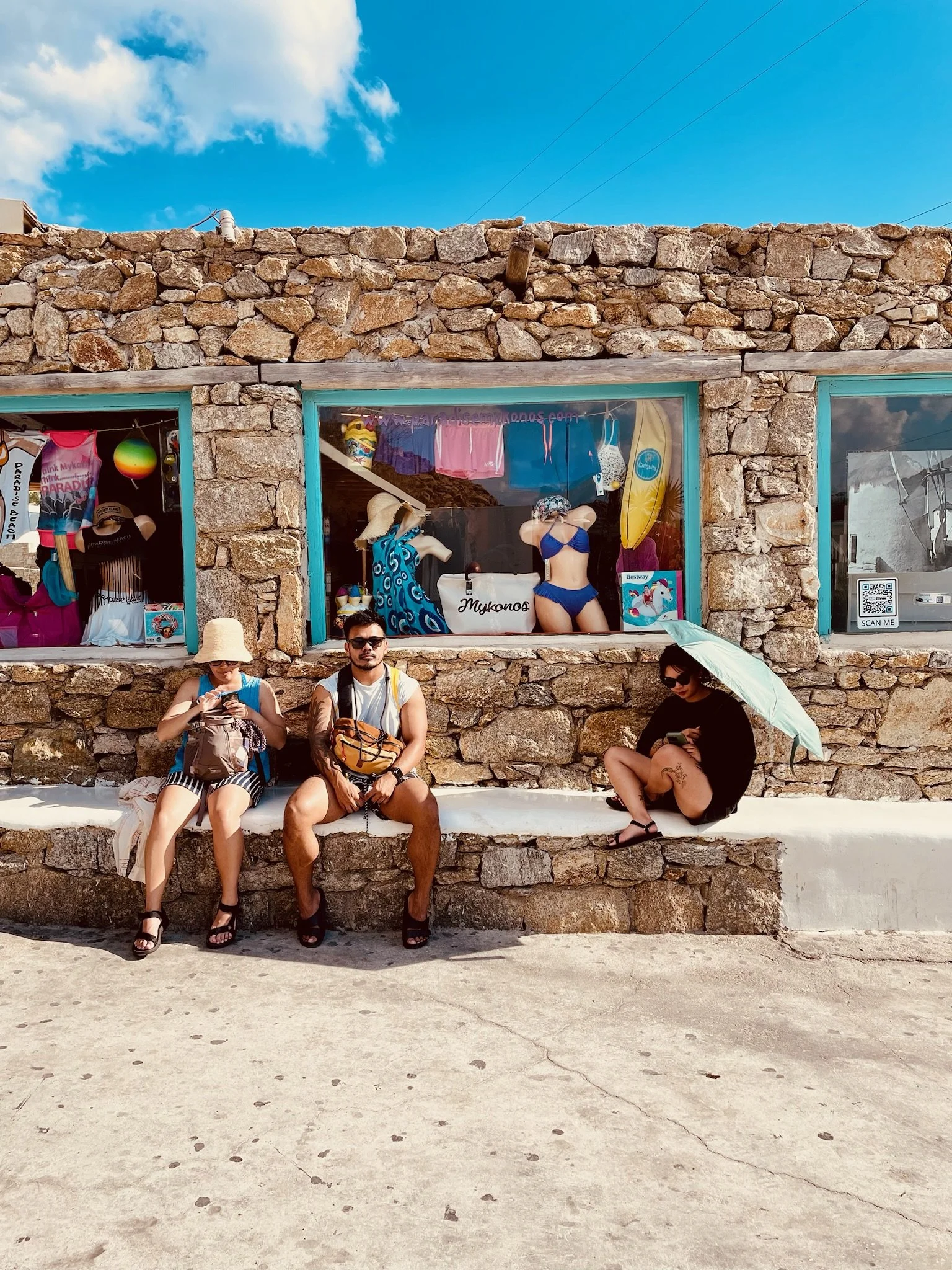 Three friends sitting outside a beachside shop in Mykonos