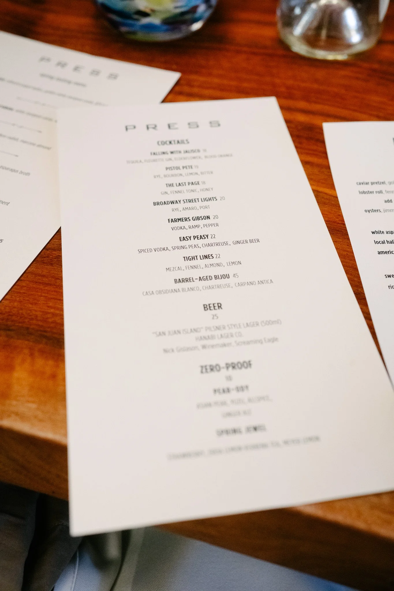 PRESS restaurant cocktail and beer menu printed on paper atop a wooden table