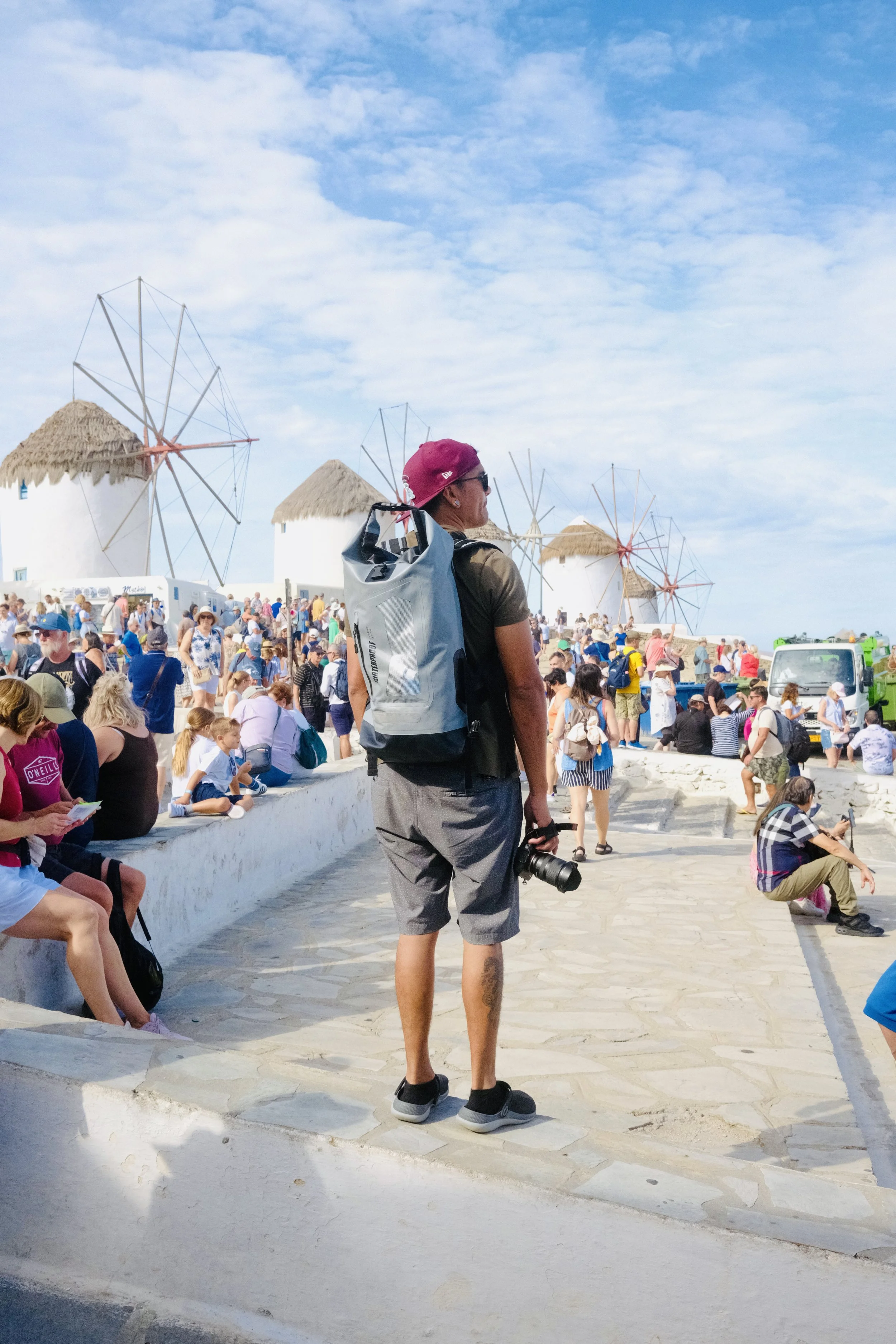 A man with a backpack standing near the windmills of Mykonos