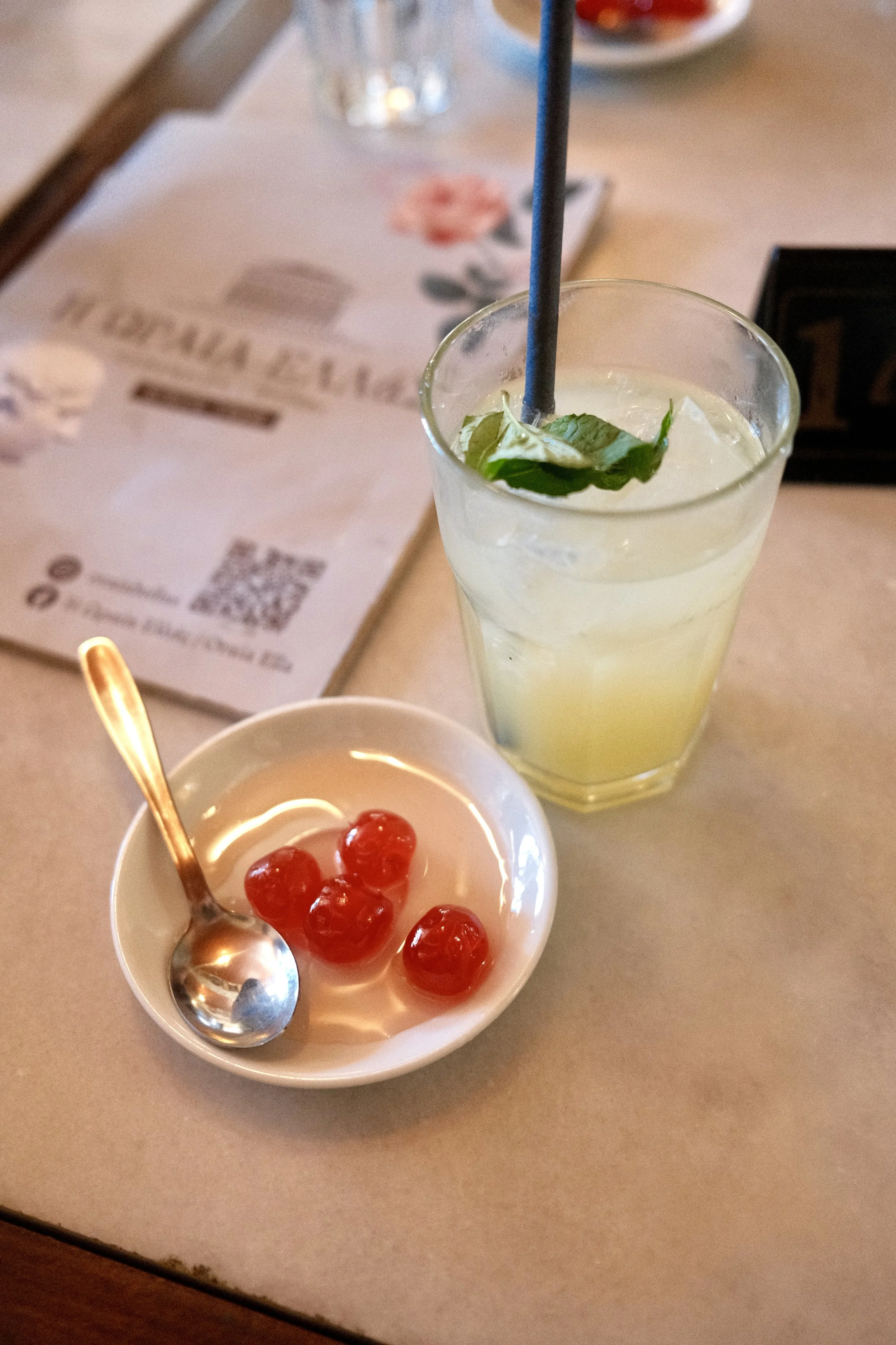 Mint lemonade and a candied fruit dessert on a marble cafe table in Athens