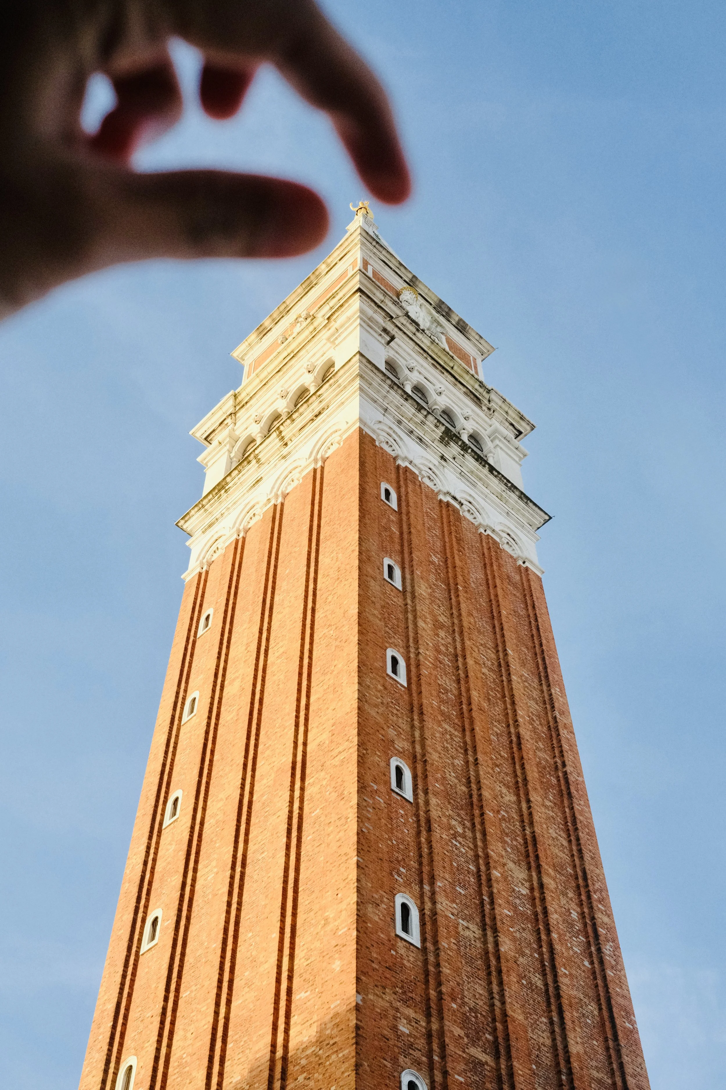Fingers framing the golden top of St Mark's Campanile in Venice
