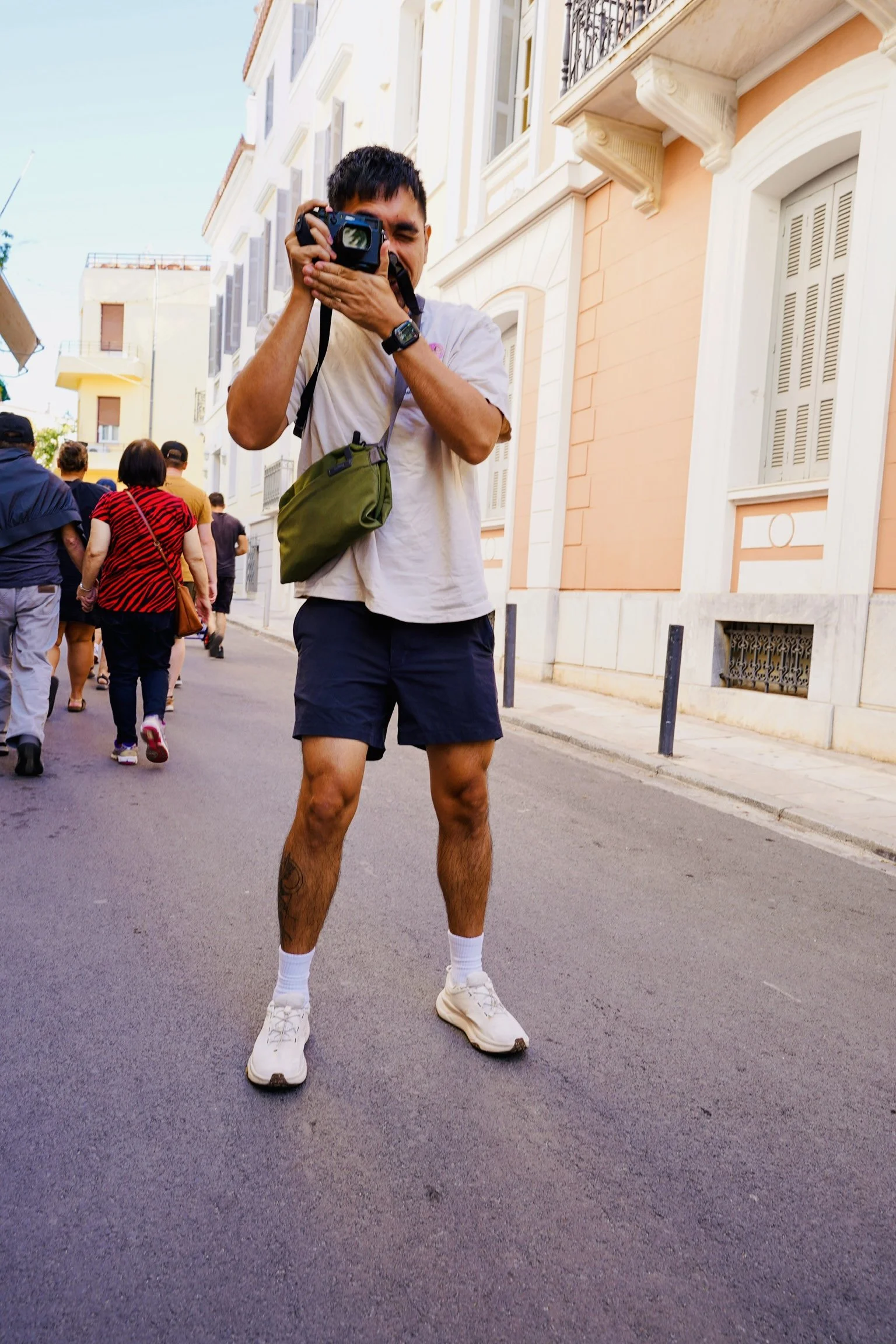 A man taking a photo with his camera on an Athens street