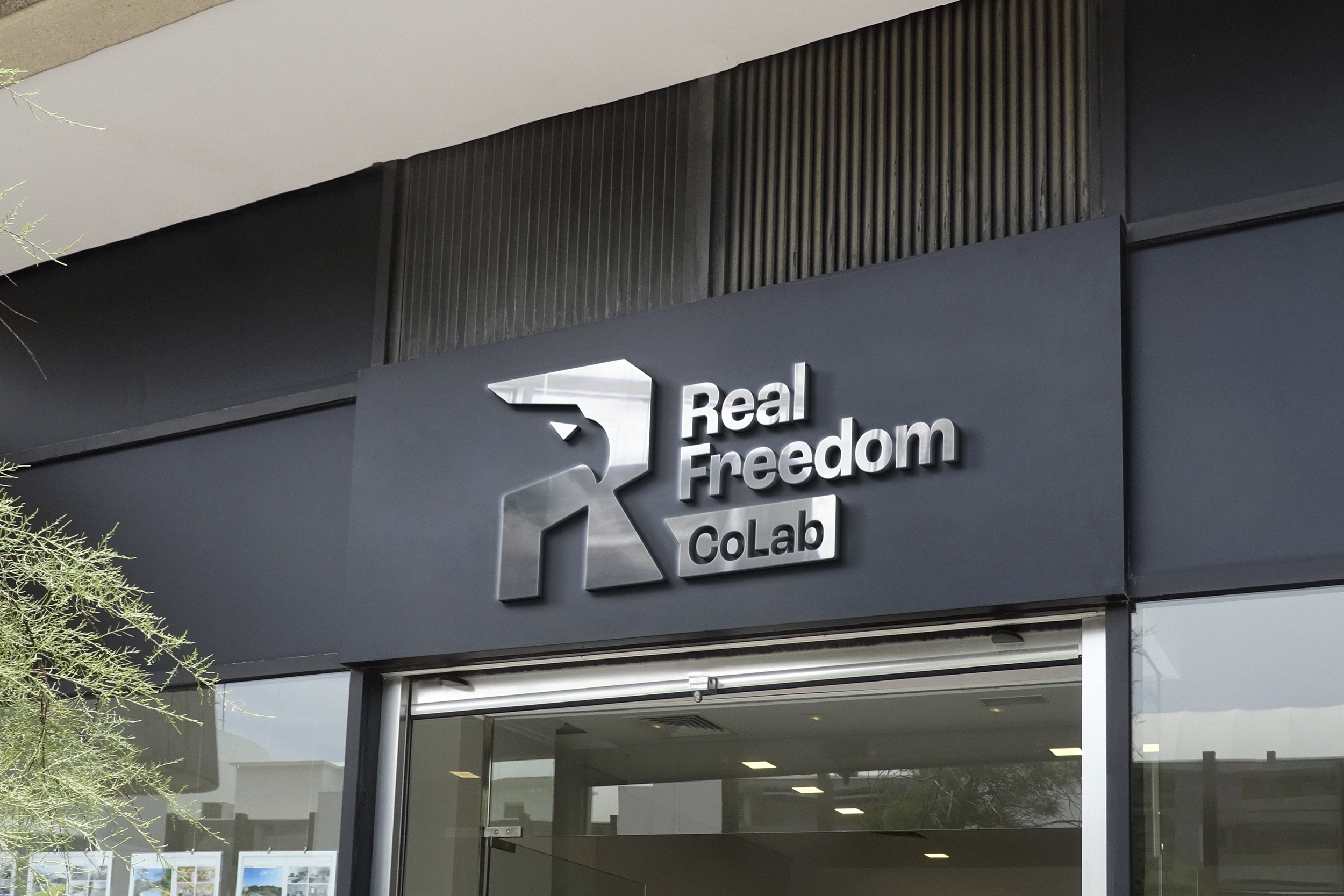 Real Freedom CoLab eagle logo as brushed metal storefront signage mockup